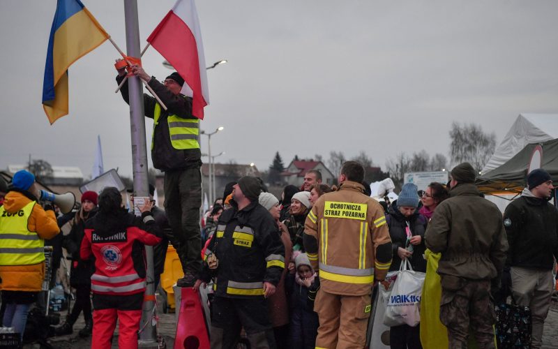 A volunteer adjusts Polish and Ukrainian flags as refugees wait for their transportation after crossing the Ukrainian-Polish border at the border crossing in Medyka, southeastern Poland, on March 9, 2022. - The UN says 143,000 fled Ukraine in the last 24 hours, with the total number of refugees topping 2.15 million -- and more than half of those in Poland. (Photo by Louisa GOULIAMAKI / AFP) (Photo by LOUISA GOULIAMAKI/AFP via Getty Images)